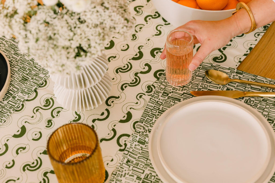 Green and white patterned linen cotton blend fabric tablecloth styled with a citrus-inspired place setting